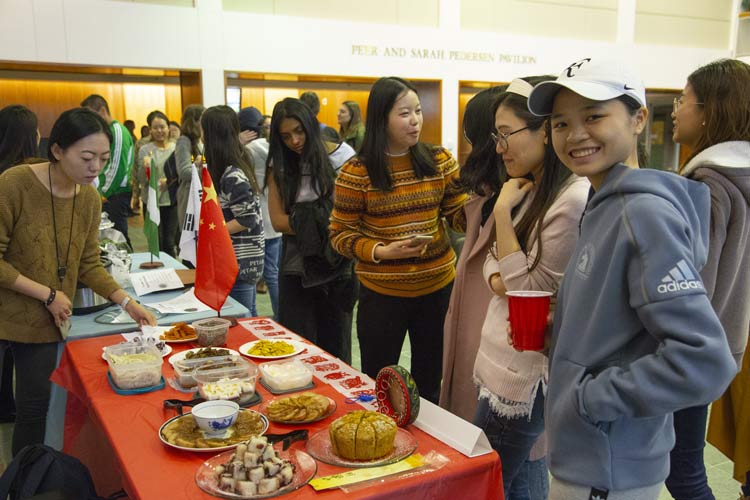 students in line for food, one smiling at the camera
